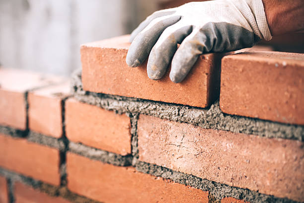 Home close up of industrial bricklayer installing bricks on construction site